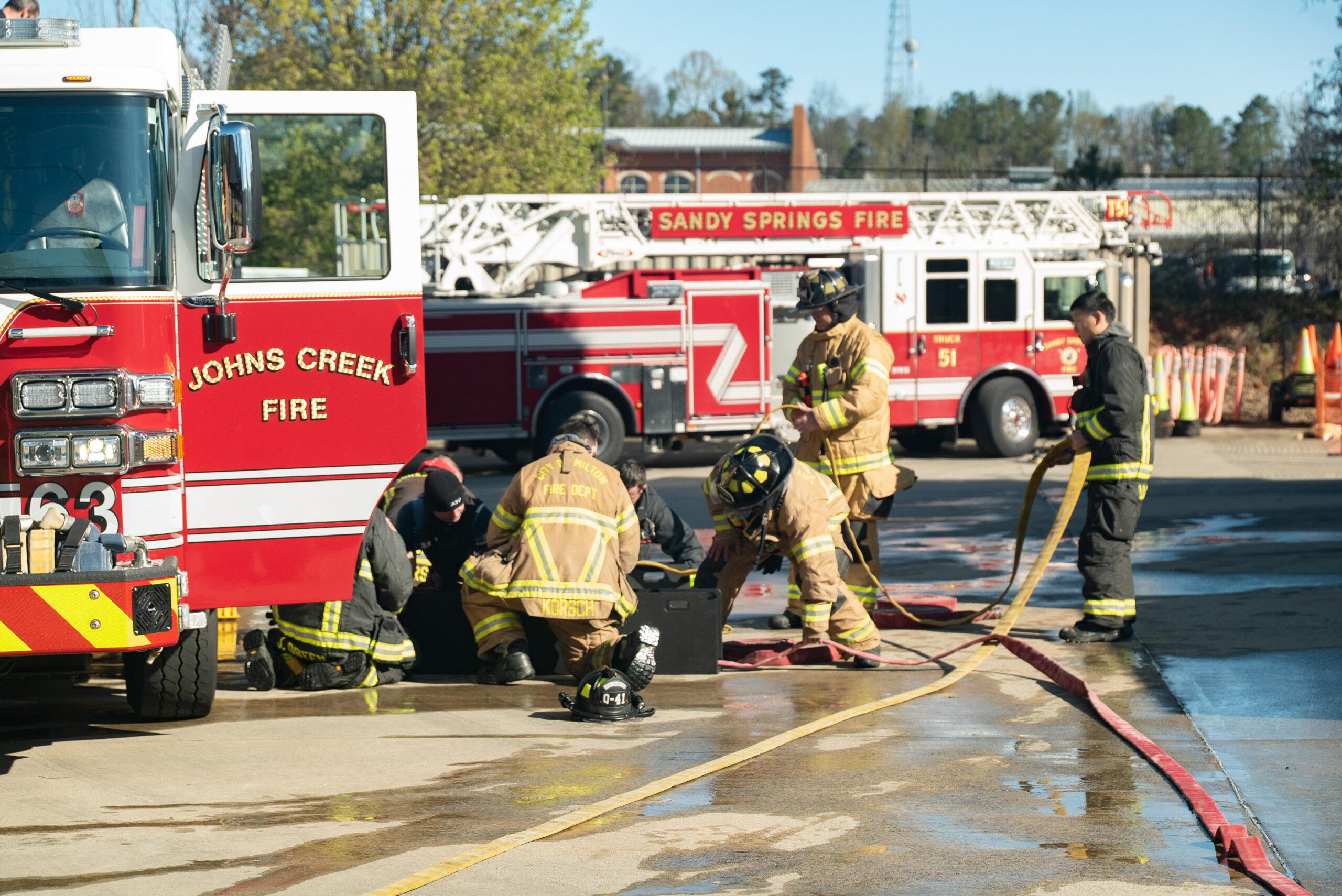 Fire department training with hoses near a fire truck