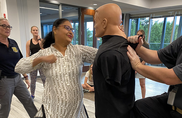 A woman performing self-defense moves on a dummy.