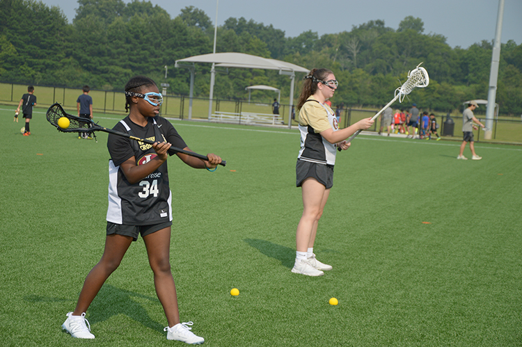 Two lacrosse players on the athletic field at Cauley Creek Park
